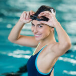 Portrait of fit young woman wearing swimming cap and goggles at