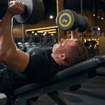 Caucasian male weightlifter bench-pressing in fitness center
