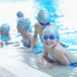 group of happy kids children   at swimming pool class  learning