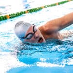 Senior man swimming in an indoor swimming pool.
